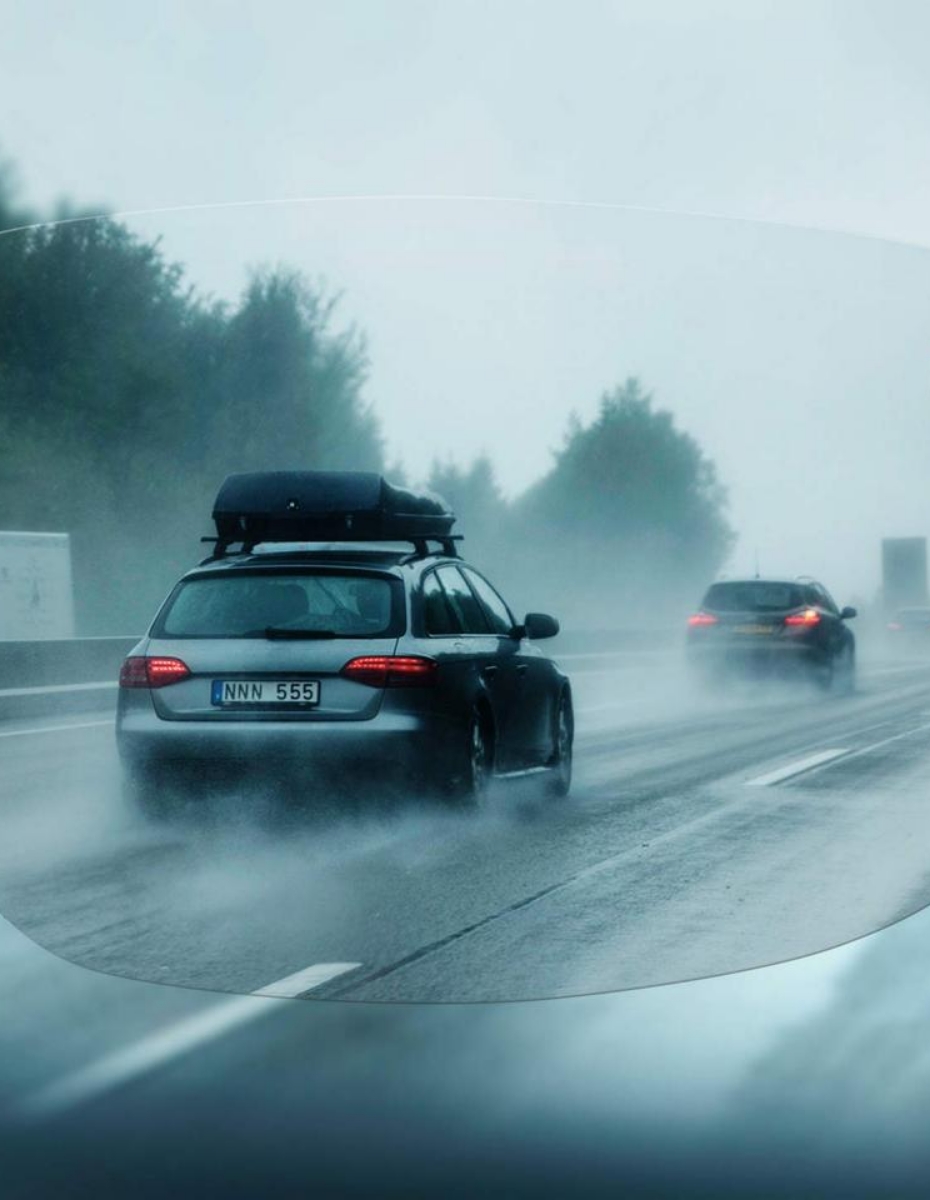 Blick durch Brillenglas auf regnerische Straße mit Autos.
